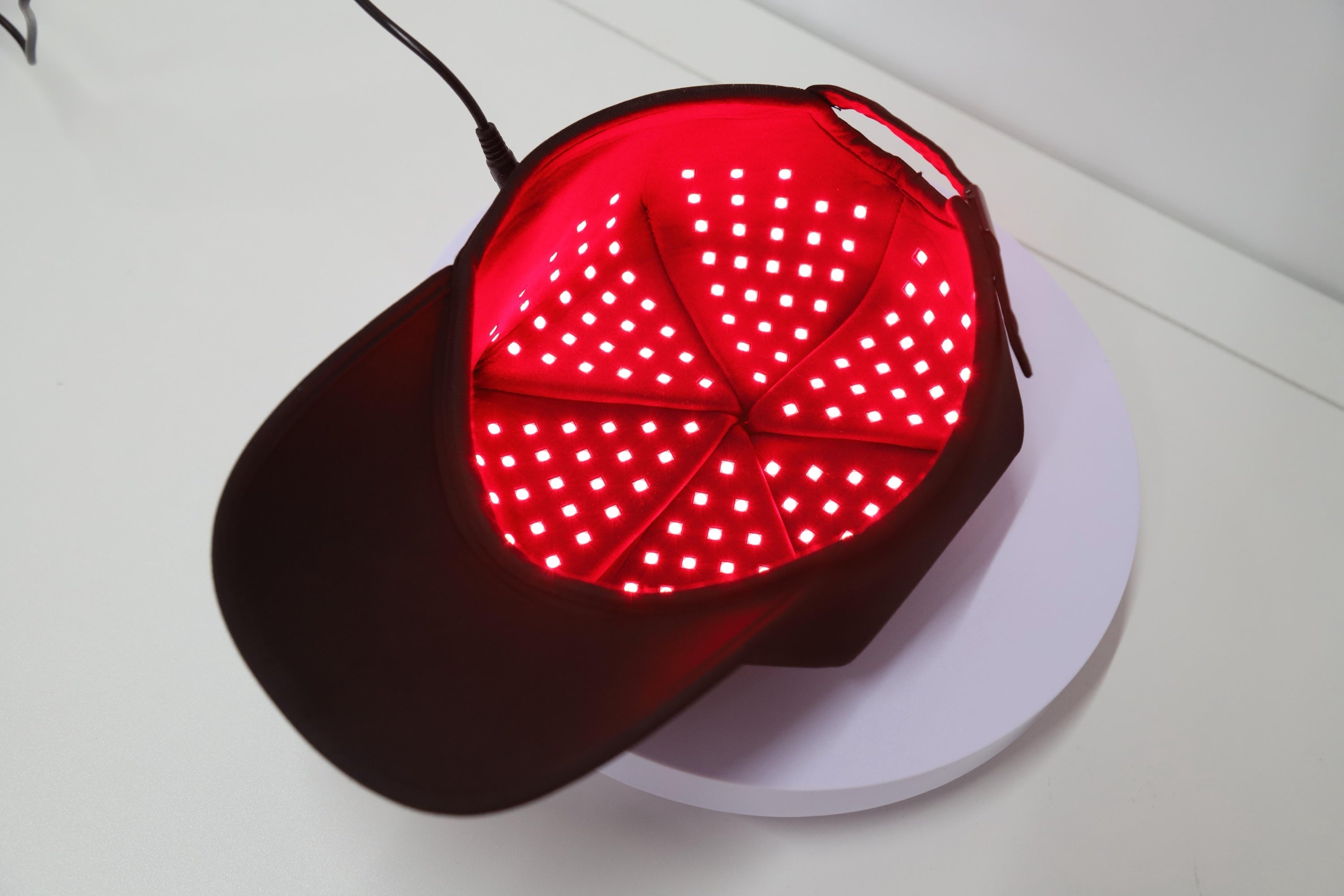 Red light therapy cap with 180 LEDs lit inside the crown